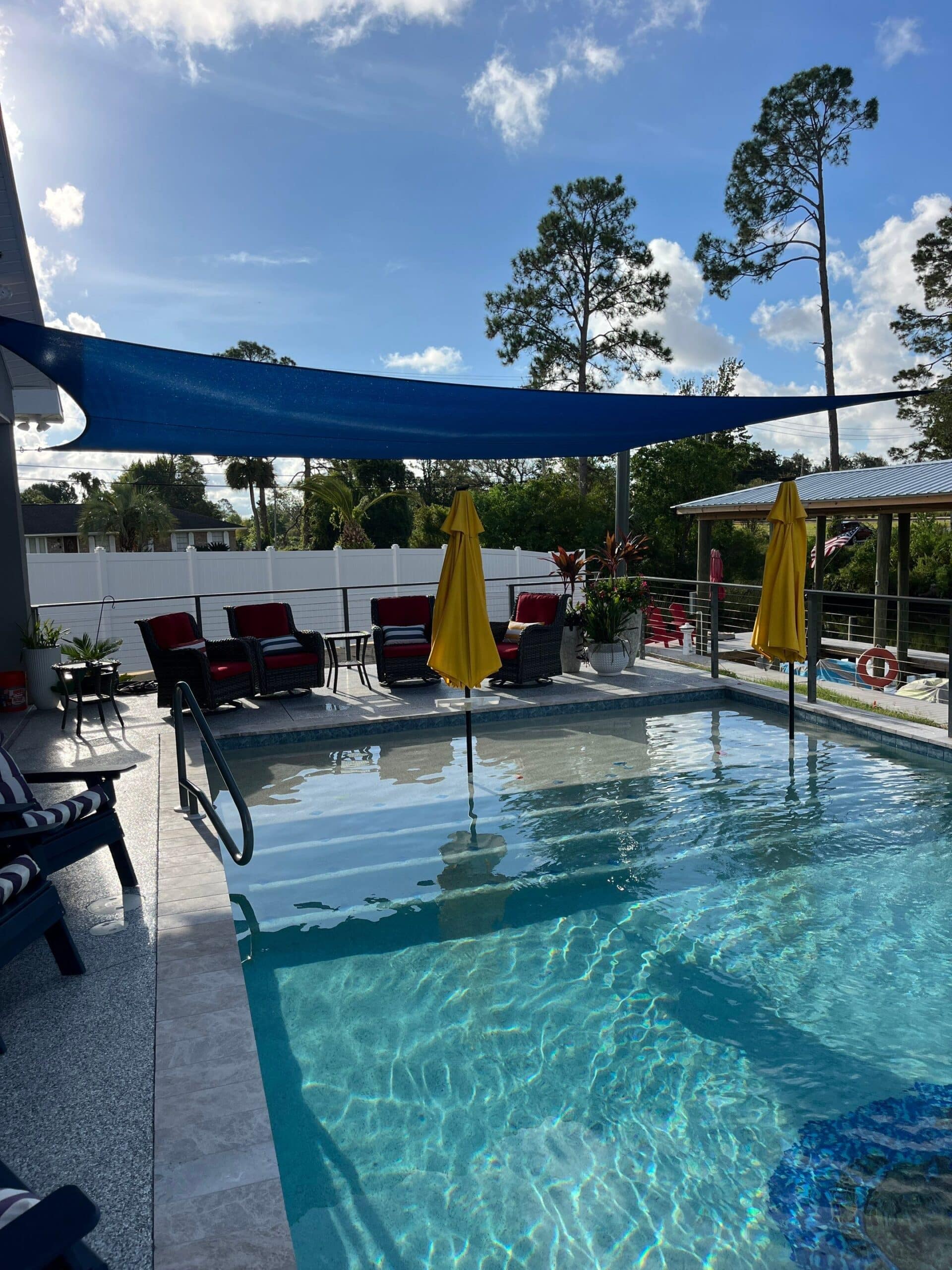 New blue sun shade sail at a home pool in Panama City Beach installed by Recovery Room Awning & Shade providing for custom shade structures and storm protection solutions in Panama City & Northwest Florida